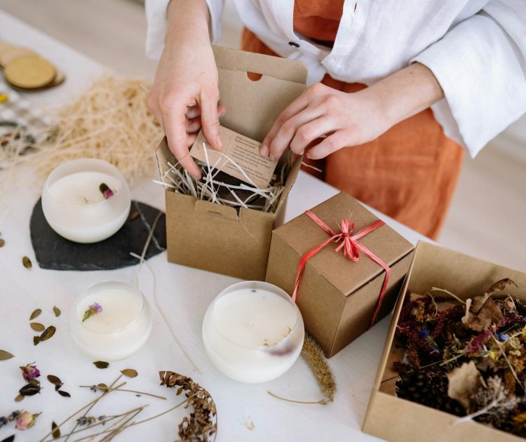 Person assembling eco-friendly candle gift boxes with natural materials.