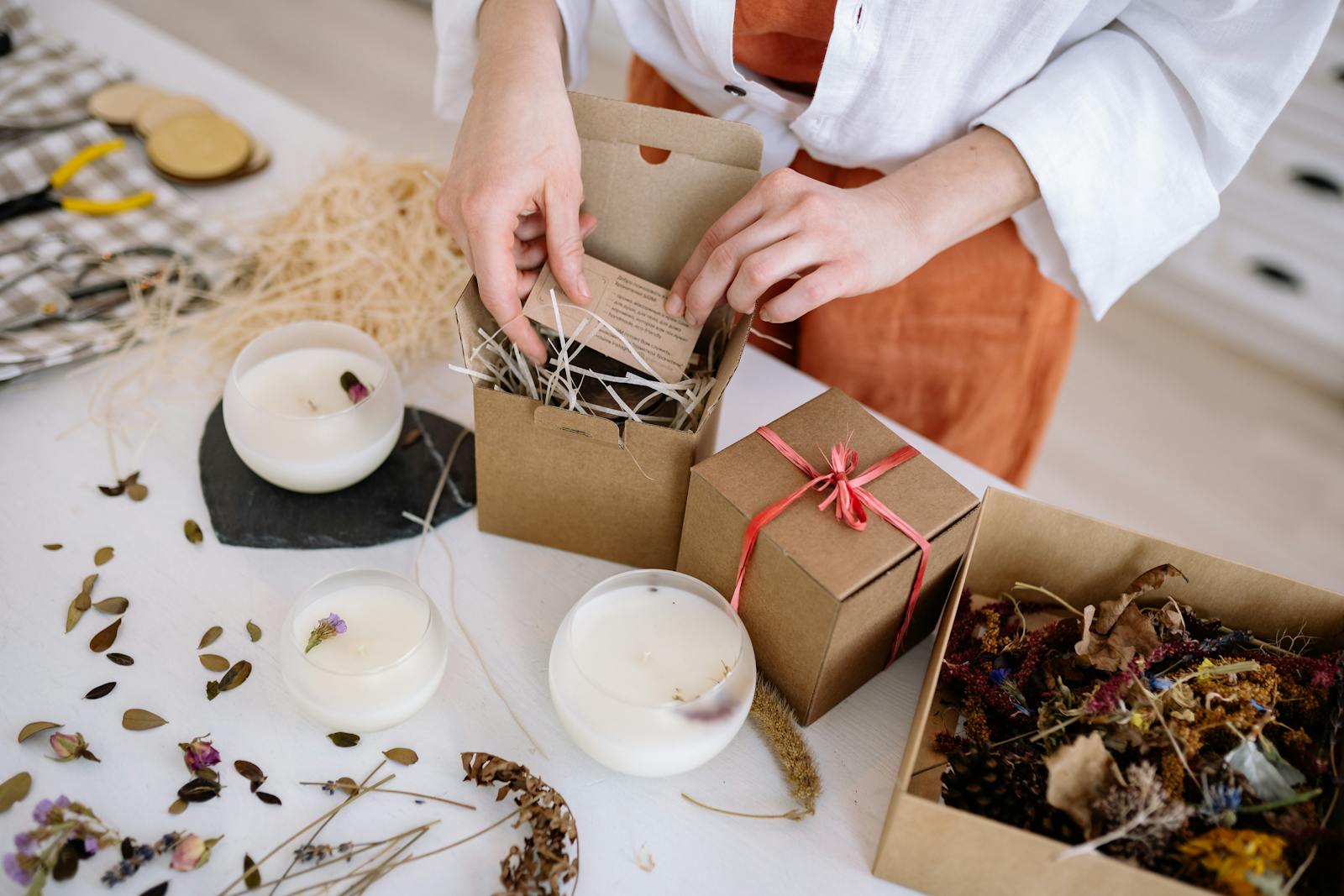 Person assembling eco-friendly candle gift boxes with natural materials.